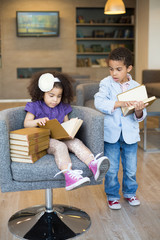 Brother and sister reading book in business center