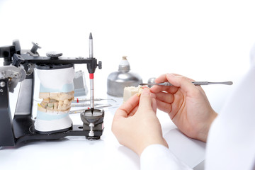 Dental technician working with articulator in dental laboratory