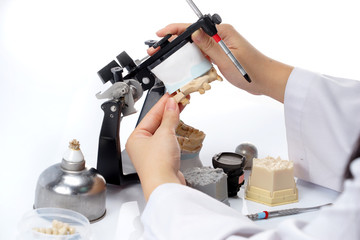 Dental technician working with articulator in dental laboratory