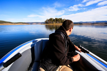 Fisherman on his boat traveling to small island in the horizon 