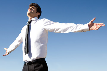 Happy business man raised arms with blue sky