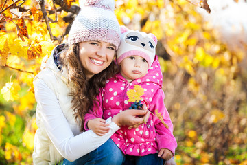 Young mother and her cute girl have fun in autumn vineyard