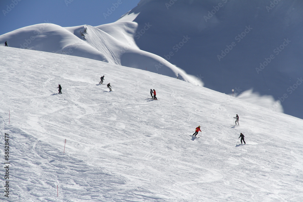 Wall mural skiers going down the slope at ski resort