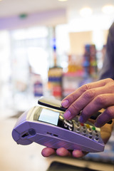 Man paying with NFC technology on mobile phone, in pharmacy