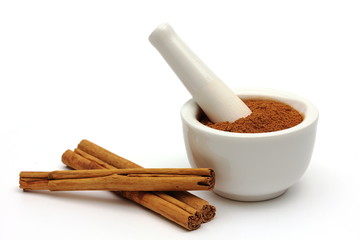 Ground cinnamon in a bowl with cinnamon sticks