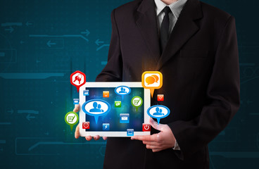 Businessman presenting modern tablet with colorful social signs