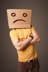 Young man with a brown cardboard box on his head with sad face