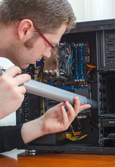 Man cleaning computer with hoover