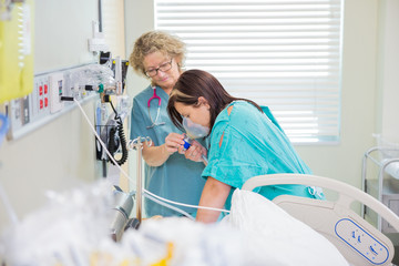 Pregnant Woman Breathing Through Oxygen Mask While Nurse Assisti
