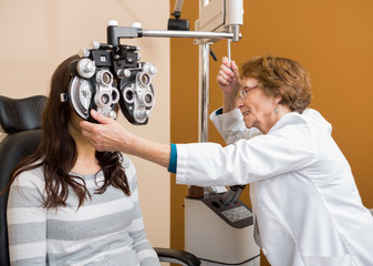 Fototapeta na wymiar Optometrist Examining Young Woman's Eyes