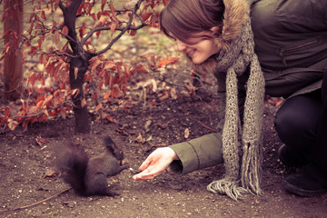 Young woman feeding a squirrel with a walnut