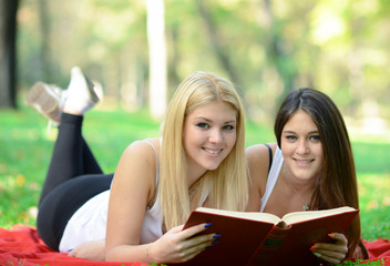 Fototapeta premium Two girls reading book in park