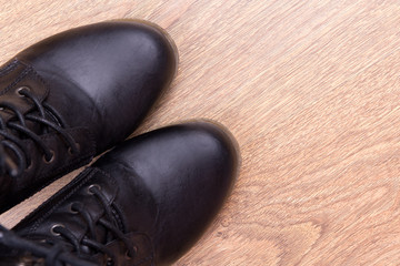 black leather boots over wooden background