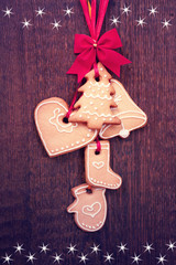 Gingerbread cookies hanging over wooden background