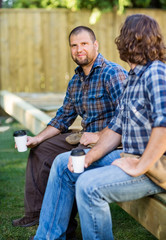 Obraz premium Confident Worker Holding Disposable Cup While Sitting With Cowor