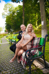 young couple sitting on bench at park and looking at camera