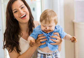 Mother Holding Baby Boy With Cake Icing On Face