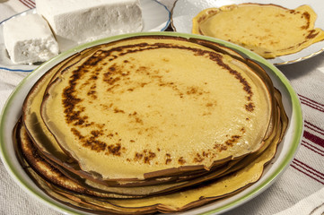 Plate with homemade pancakes and white cheese block