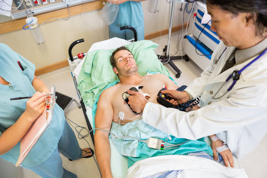 Doctor Defibrillating Male Patient In Hospital