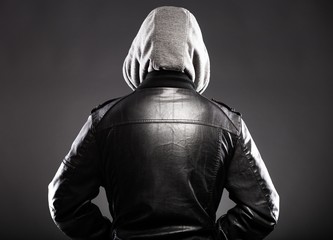 Young man in leather jacket and hood rear view
