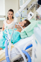 Woman Looking At Male Patient Resting On Bed