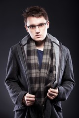 Obraz premium Elegant young man in coat and glasses