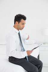 Businessman with cup reading newspaper at hotel room