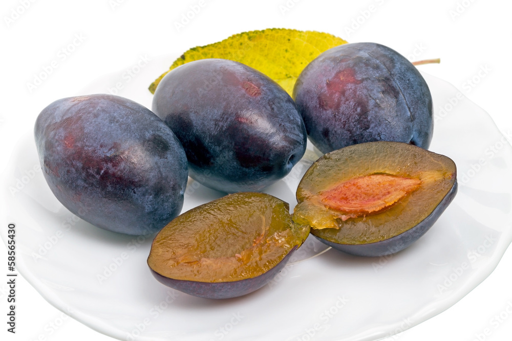 Wall mural Four plums on a white plate