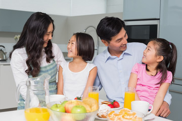 Obraz na płótnie Canvas Cheerful family of four enjoying healthy breakfast in kitchen