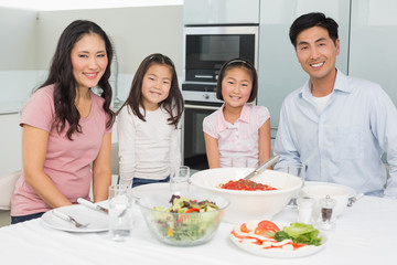 Smiling family sitting at dining table in kitchen
