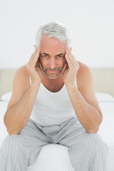 Mature man suffering from headache in bed