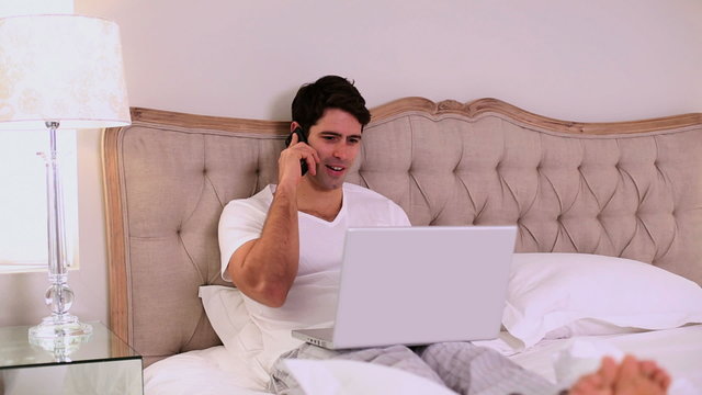 Happy handsome man working in bed