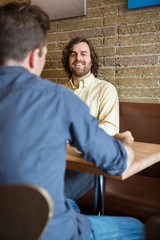 Man With Friend Sitting At Coffeeshop