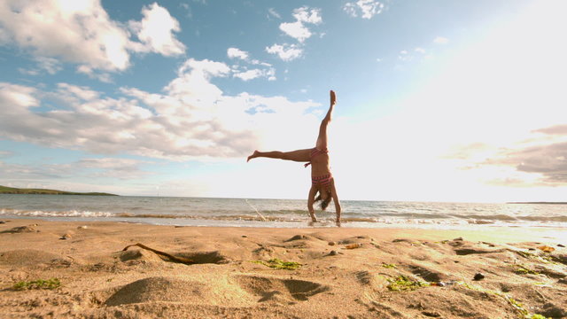 Woman doing cartwheel at the beach