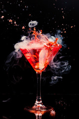 red cocktail with splash and ice vapor