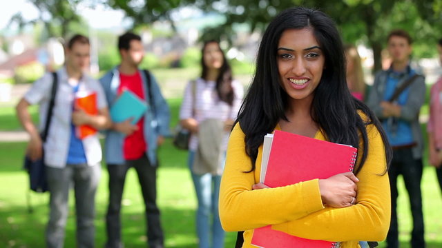 Student smiling at camera with friends standing behind her
