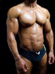 Shirtless male bodybuilder in trunks, really muscular body