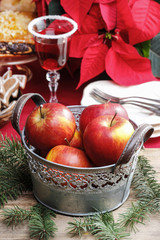 Silver bucket of red christmas apples. Poinsettia flower