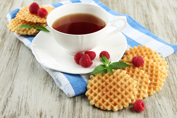 Cup of tea with cookies and raspberries on table close-up