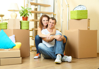 Young couple sitting in new house on staircase background