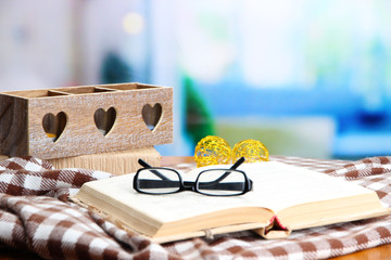 Composition with old book, eye glasses, candles, and plaid