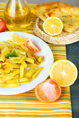 Ruddy fried potatoes on plate on tablecloth close-up