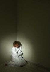 Mentally ill man in strait-jacket in room corner