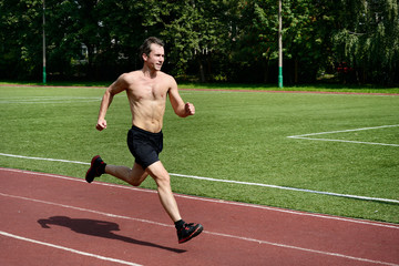 Obraz premium Athlete runner trains at the stadium