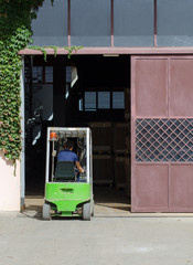 Warehouse worker loading boxes by forklift