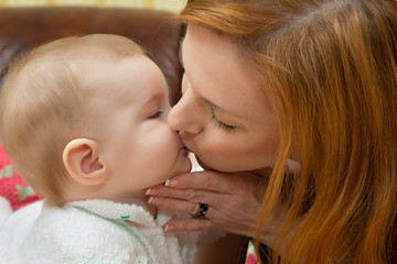Любящая мама нежно целует своего ребёнка