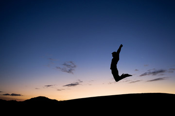silhouetted man jumping in sunset