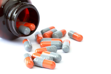 Grey and orange capsules with bottle on white