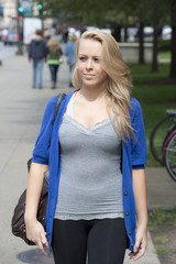 A young attractive female model walking down a sidewalk on a cloudy day in Chicago.