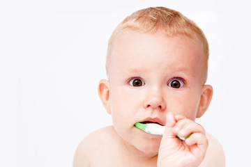 Cute baby brushing his teeth on white